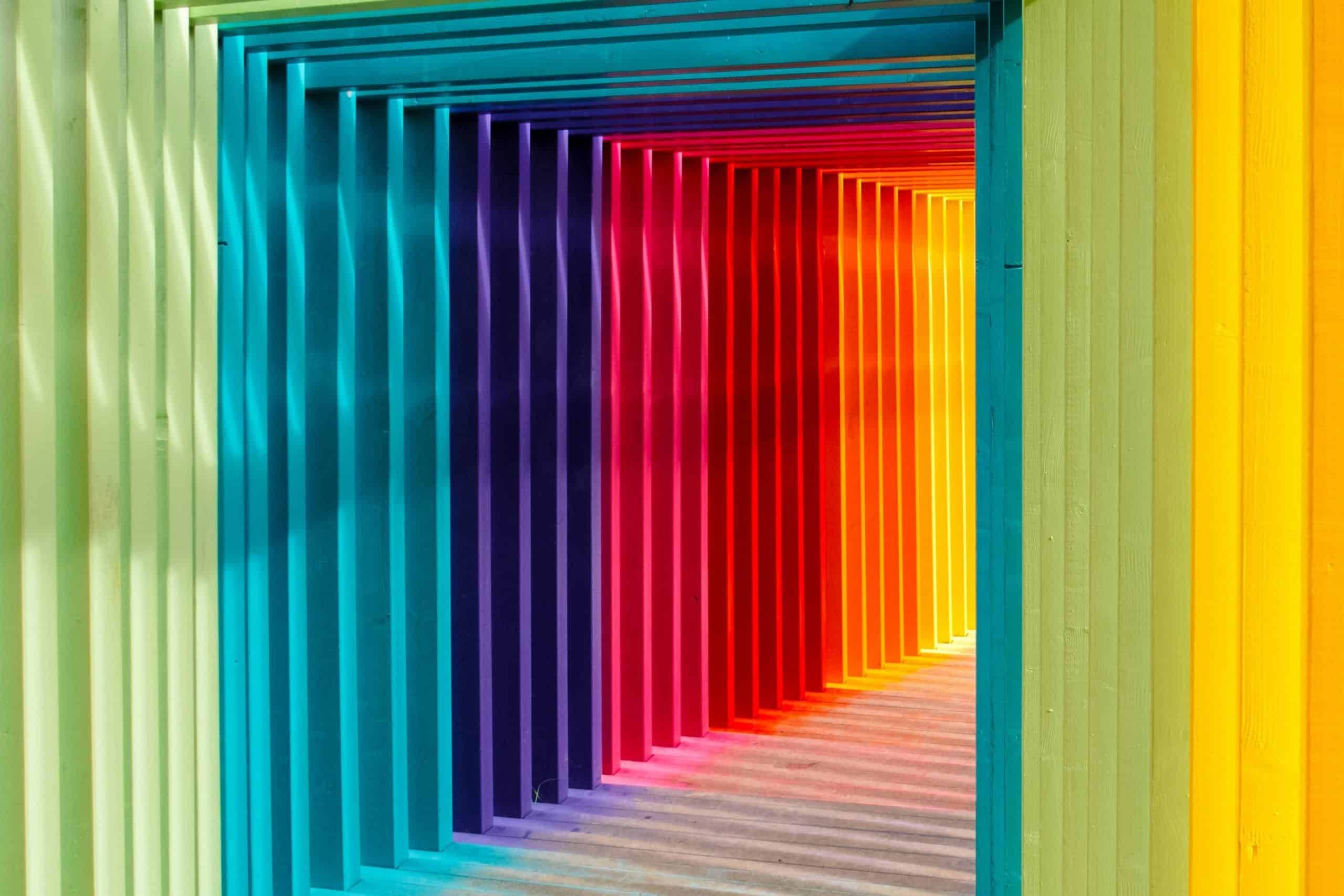 Vibrant rainbow-colored wooden corridor with multicolored vertical slats, modern design, creative space, colorful interior, architecture, innovative design, SOHO Creative Group.
