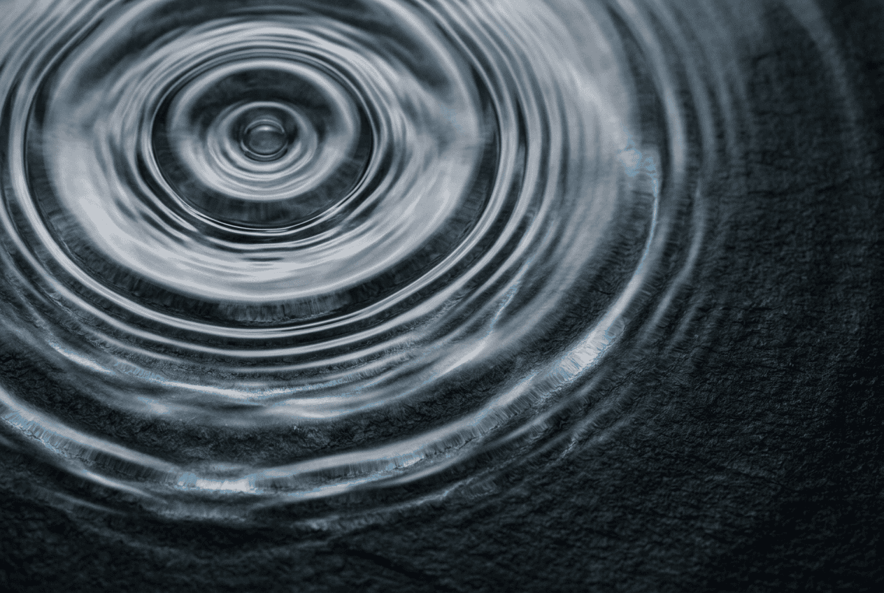 Light refracting through rippling liquid over a dark surface, a visual metaphor for brand distinctiveness and craft